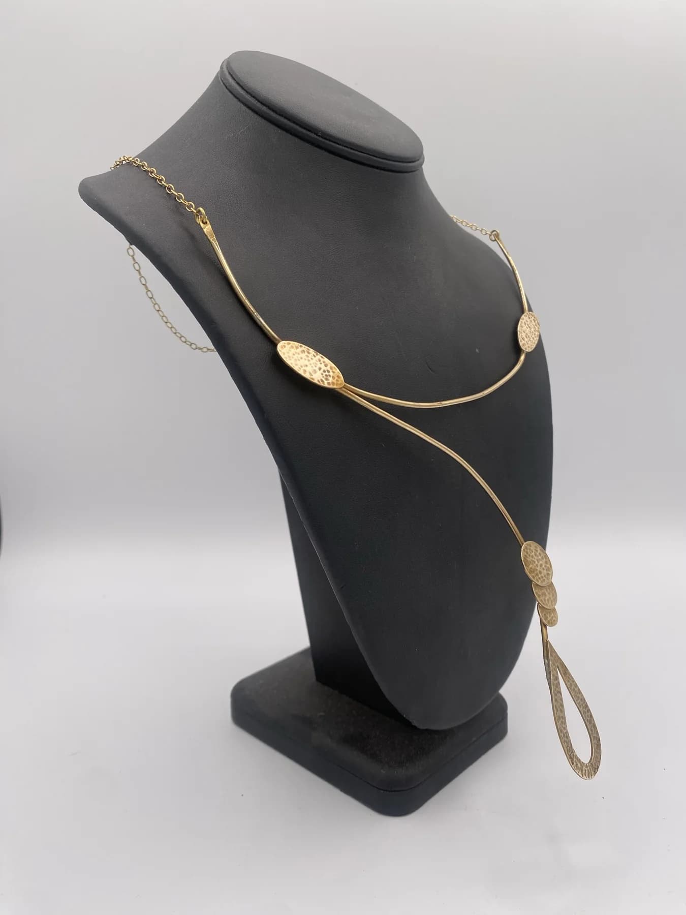 Long necklace arranged around a dark display form.