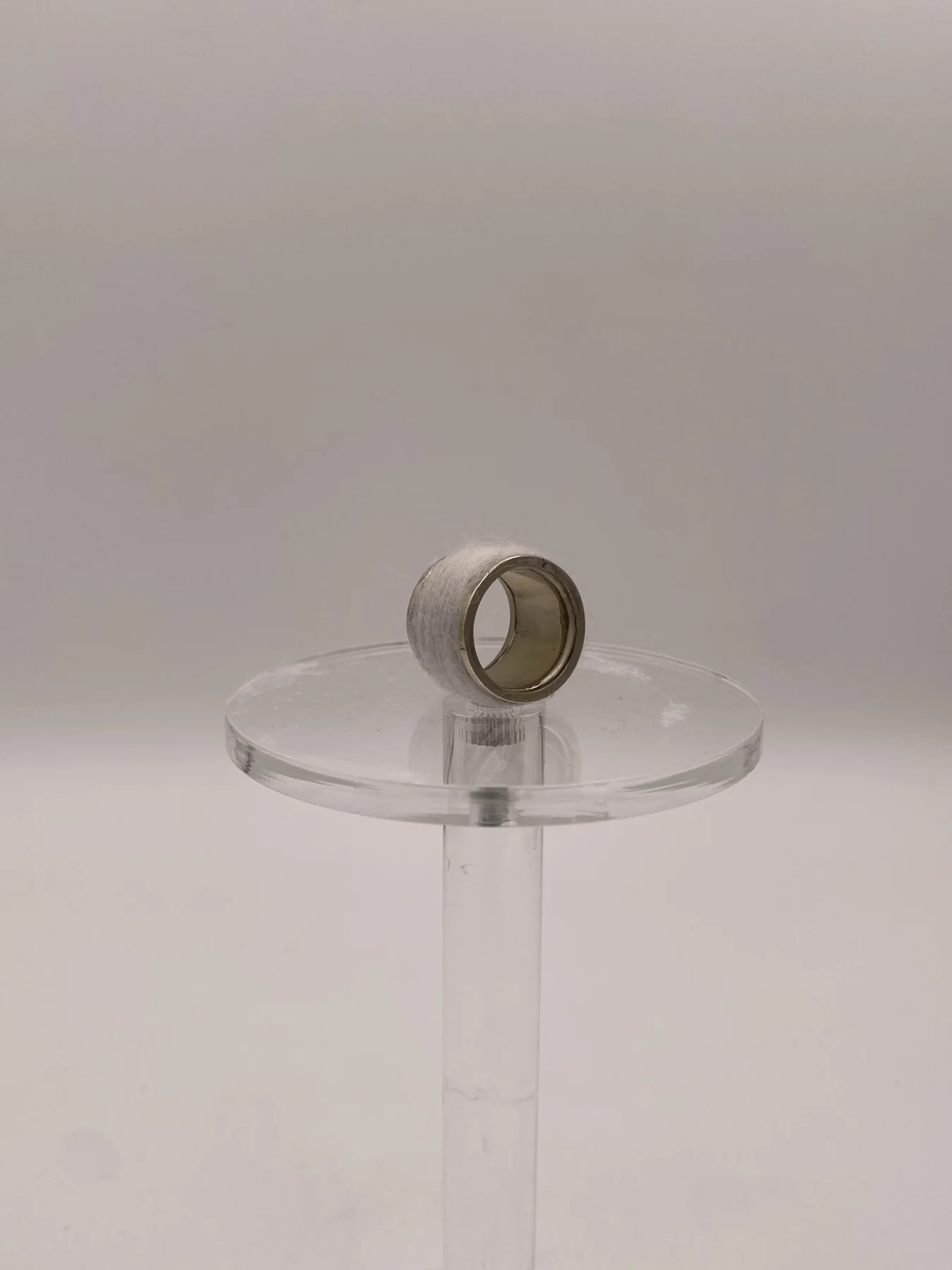 Sculptural ring displayed upright on a clear stand.