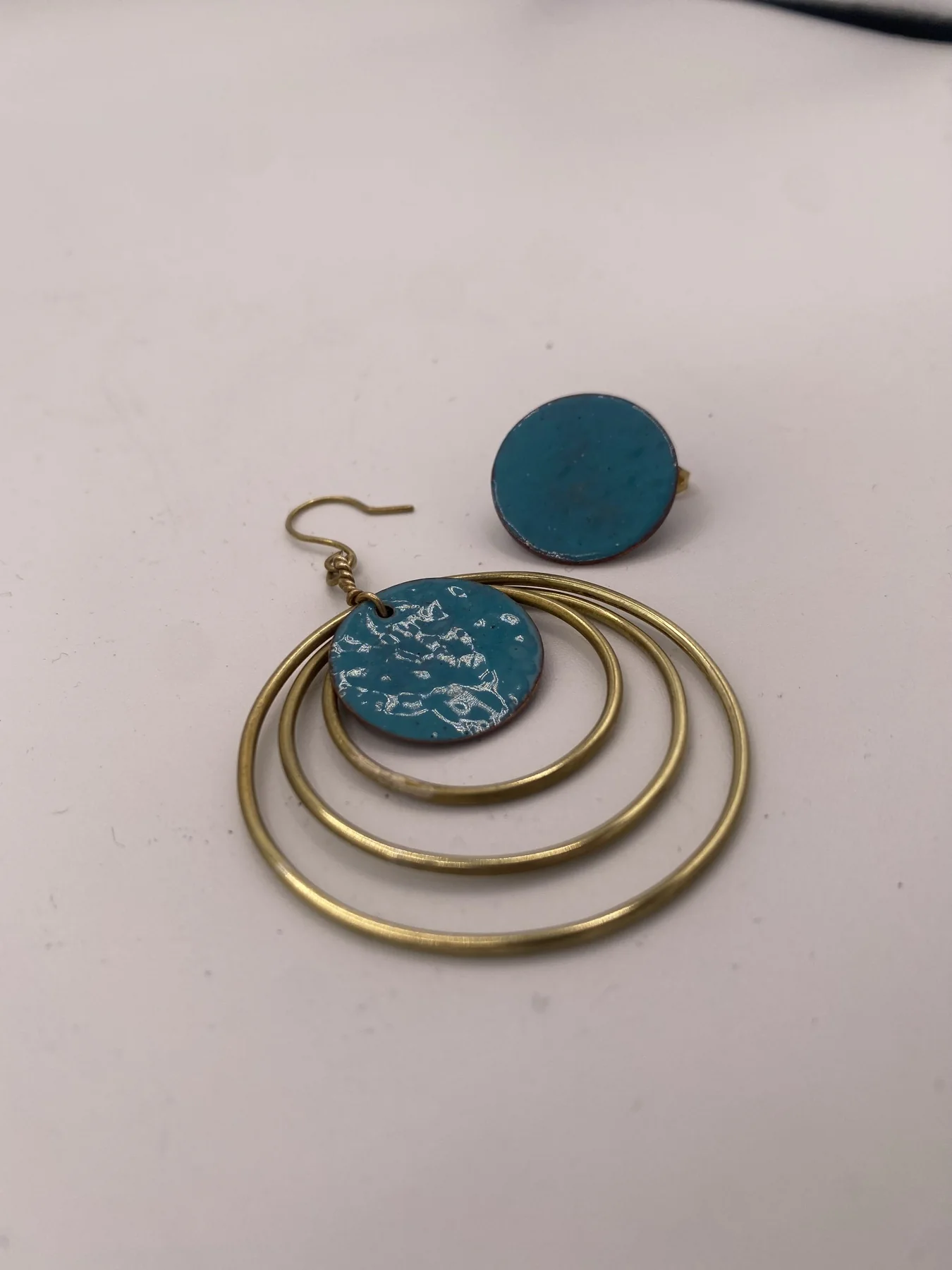 Layered circular earrings with blue round accents on a light surface.